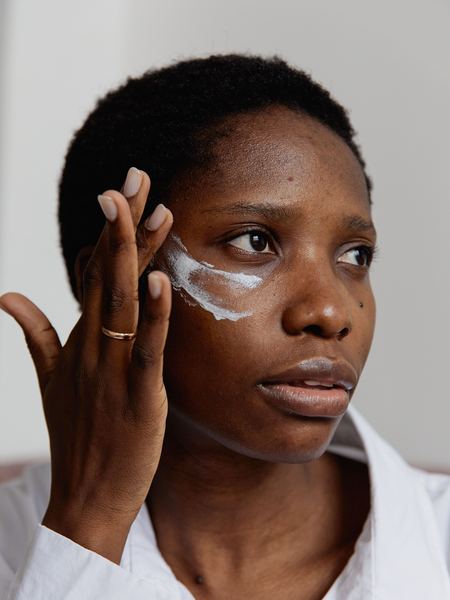 Femme à la peau foncée appliquant un soin sous l'œil